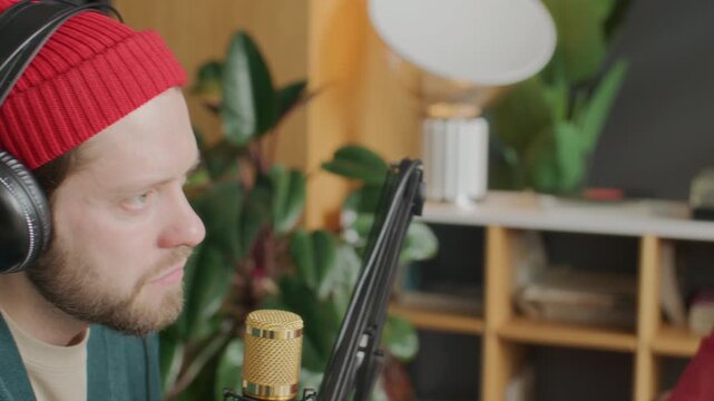 Team of three multigenerational podcast presenters wearing headphones and talking into microphones, discussing topic and sharing experience while recording new episode in studio. Panning shot