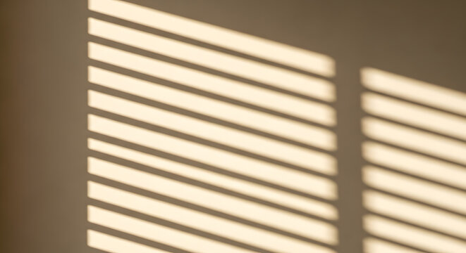 Distinctive striped shadows cast by window blinds on a textured beige wall, creating geometric patterns