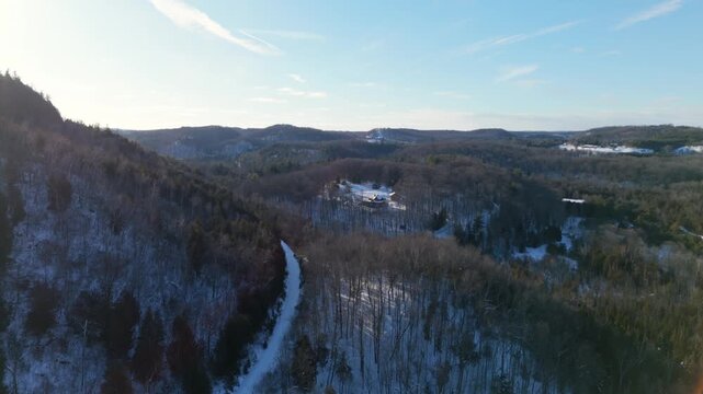 Aerial drone view of Devils Pulpit mountain in Forks Of The Credit, Caledon Ontario, showing forested hills, winter trees, winding road, and scenic natural landscape near Toronto