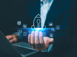 Fototapeta premium Businessman holding digital rocket launch icon with startup growth strategy interface, innovation development, investment planning, financial success and business acceleration concept.