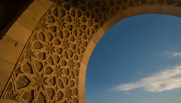 Intricate Islamic Geometric Star Carving on Ancient Stone Arch Framing Blue Sky. Traditional Seljuk Architecture Detail and Arabesque Pattern Background.