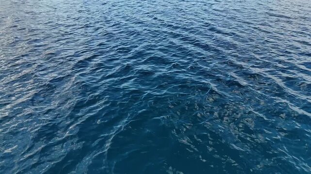 Top-down drone view above Eua Island, Kingdom of Tonga, capturing a natural pattern of pure deep blue water where delicate sandy ripples shimmer beneath the crystal-clear tropical sea