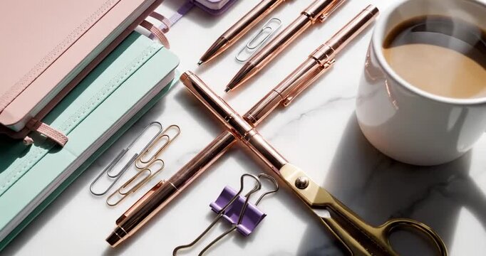 A stylish workspace scene featuring colorful notebooks, pens, and coffee on a marble table