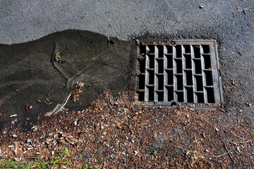 Clean water running down street into stormwater drain on a sunny winter day
