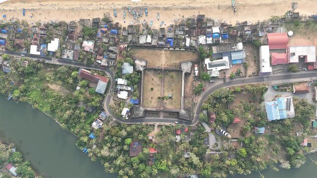 Editorial footage from Anjuthengu Fort, Kerala, India &mdash; January 20, 2026. Drone ascends higher, revealing coastline and backwater canal beside the historic fort.