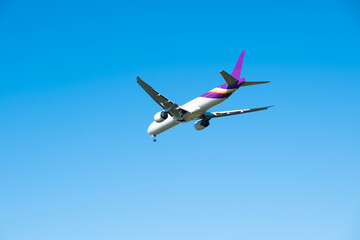 Obraz premium Passenger aircraft with landing gear down, flying in a bright blue sky. on the engines and tail, perfect for travel and transportation concepts. 