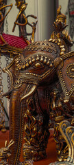 Fototapeta premium Intricately carved decorative elephant statue with metallic finish, ornate patterns, traditional craftsmanship, cultural sculpture, detailed texture, artistic display, warm tones