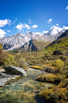 Daocheng Yading Nature Reserve mountain stream with snow peaks and autumn landscape in Sichuan China