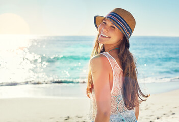 Holiday, girl and happy with hat on beach for travel adventure, summer getaway and sunshine. Smile portrait, woman or relax on sand for seaside vacation, weekend break or fresh air on tropical island