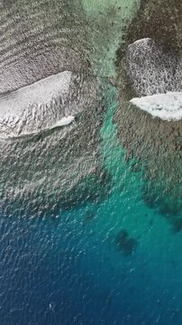 Aerial drone view above the turquoise shoreline of Eua, Kingdom of Tonga, where crystal-clear water reveals coral formations beneath the surface near the untouched tropical coast.