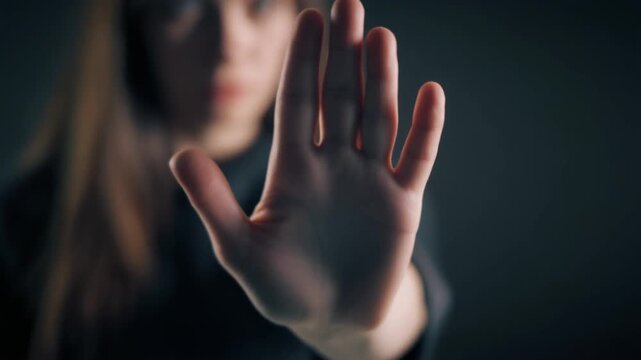 Woman showing stop gesture with open palm, concept of refusal or boundaries