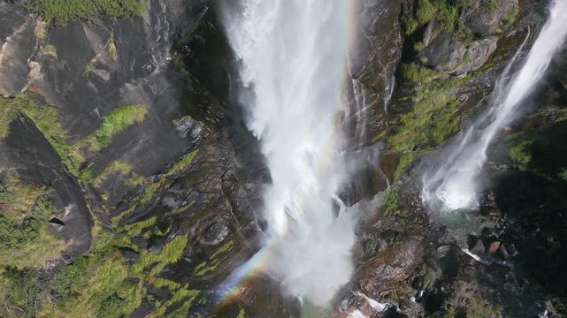 Close-up of a powerful waterfall with a rainbow forming in the spray in Valchiavenna, Italy. Aerial drone directly above