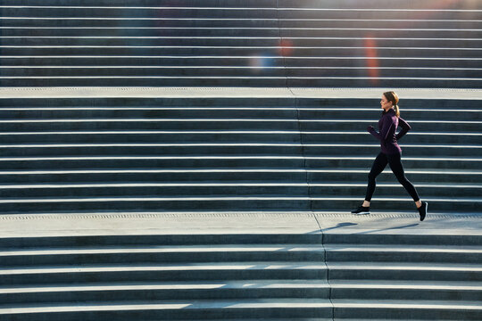 Woman, fitness or runner with stairs for exercise, workout or outdoor training in city. Active, female person or running profile with staircase for cardio challenge, health or wellness on urban space