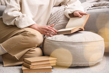 Young woman reading book on floor at home, closeup