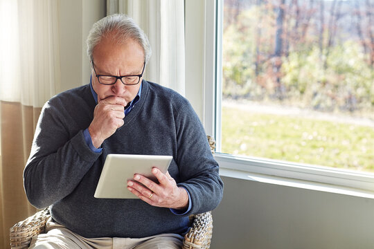 Thinking, home and senior man on tablet for communication, social media and online puzzle game. Retirement, relax and person on digital tech for website, solution and crossword answer in living room