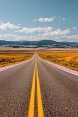 Obraz premium Long empty highway stretching through the autumn countryside into a distant horizon for road trip travel marketing background with copy space under a blue sky