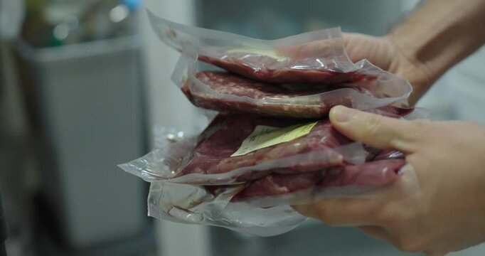 Close-up of hands holding vacuum-sealed raw meat, representing food storage, freshness, hygiene, and modern meat packaging.