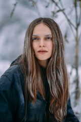 Naklejka premium A striking portrait of a brunette woman completely covered in delicate frost . Her eyelashes, eyebrows, hair, and clothing are intricately frosted.