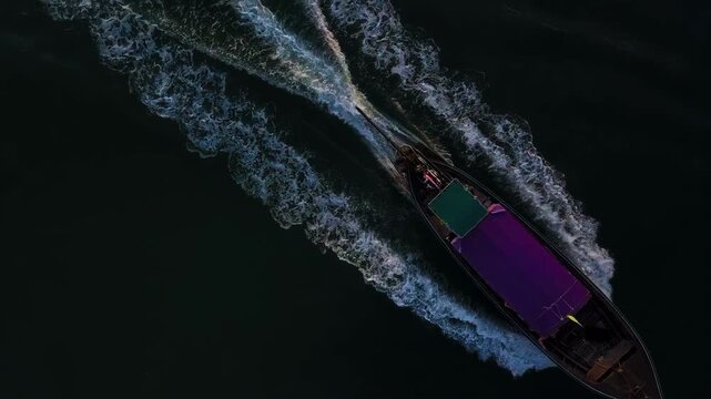 High angle aerial shot of a Thai longtail boat cruising through a calm estuary near Nopparat Thara Beach during golden hour. Perfect for travel documentaries and tropical vacation promos.