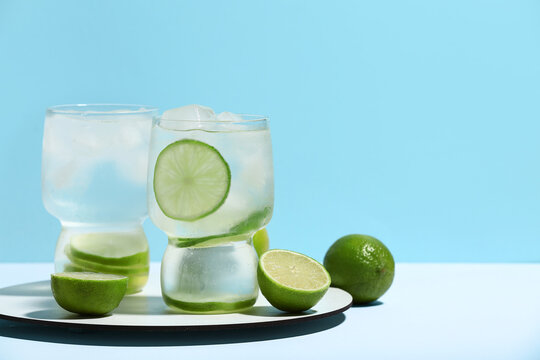 Glasses of lime infused water on white table against blue background
