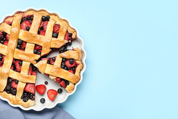 Baking dish with tasty berry pie on blue background © Pixel-Shot