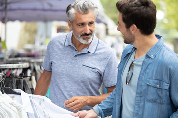Obraz premium two men looking at clothing in a street market