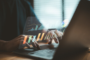 Person analyzing business data charts on laptop with futuristic digital interface
