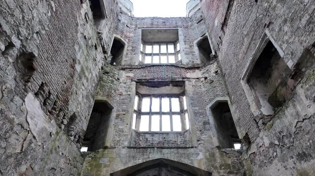 Interior View of Ancient Ruined Castle Architecture with Crumbling Stone Walls, Large Mullioned Windows, and Traditional Lattice Gate