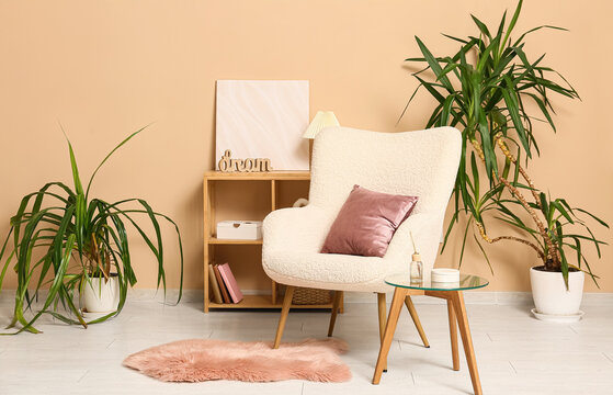 Armchair with coral cushion near beige wall in interior of living room