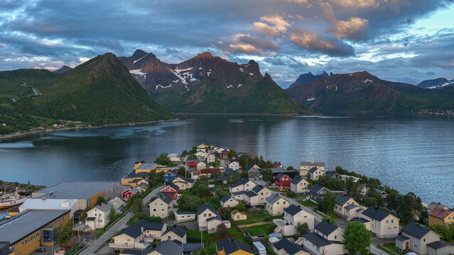 12 july 2025, Hus&oslash;y, Norway. Aerial, drone view of little village Husoy and island in &Oslash;yfjorden fjord during sunset. Beautiful nature, mountains surrounding fjord, wonderful golden reflection in the w