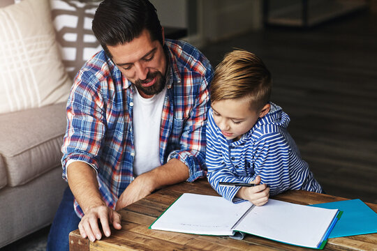 Study, child and dad with homework help in home for literacy support, test preparation and advice. Education, father and kid with book at table for language activity, writing development and guidance