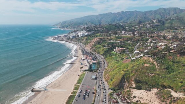 High aerial shot flying over the Pacific Coast Highway at Will Rogers State Beach on a spring day in Pacific Palisades, California. 4K