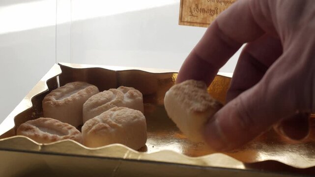 Hand selecting marzipan figures from a golden box for tasting
