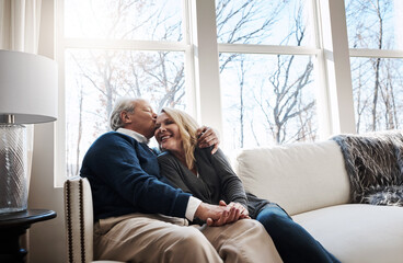 Fototapeta premium Senior couple, kiss and holding hands at house with love, partner affection and bonding together. Elderly people, happiness and embrace with admiration, retirement and relationship commitment on sofa