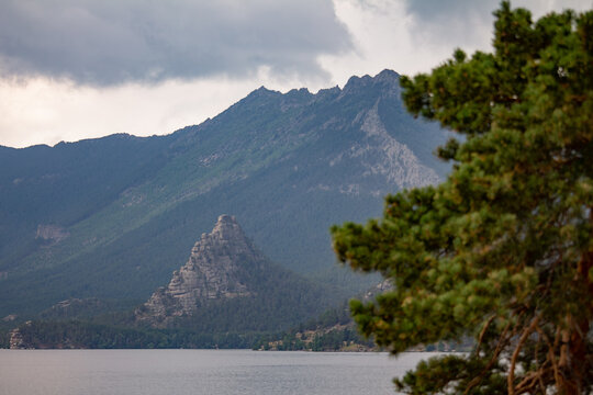 Scenic landscape of Burabay National Park with a calm lake, rocky mountains, and a pine tree in the foreground. Beautiful nature of Kazakhstan.