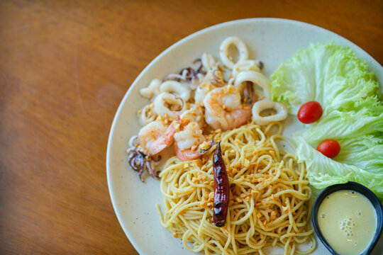 Spaghetti in a dish with seafood (shrimp, squid), Asian street food.