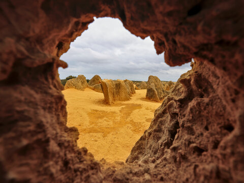 The Pinnacles Desert, Nambung National Park, framed by hole in rock. Near Cervantes and Jurien Bay, Western Australia. Limestone rock formation pillars. Yellow sand. Approximately 200 kilometers north