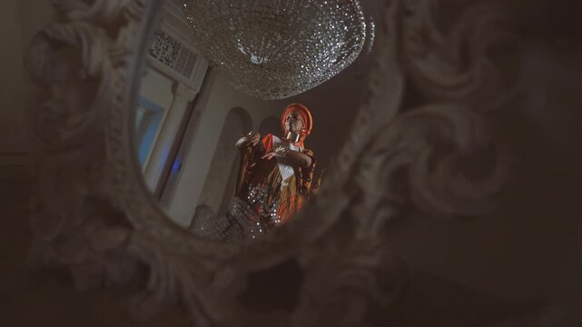 Pretty african female dancer dancing in royal palace, view in mirror, dance show . Beautiful black woman in ethnic african gown performing traditional ritual dance in luxury interior, seductive dance