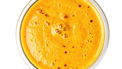 A close-up of a vibrant, orange smoothie in a clear glass, viewed from directly above