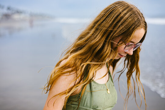 Blond teen young girl walking with sea blown hair on beach