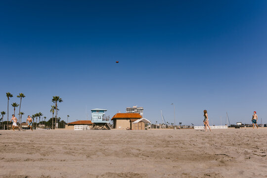 Teen kids throwing football on beach with blue sky and palms