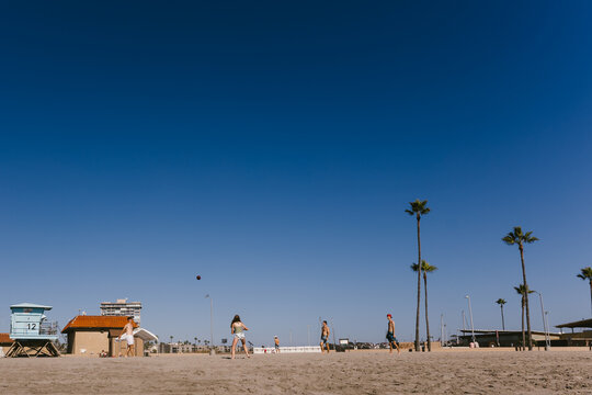 Young adults playing football on the beach in the sand