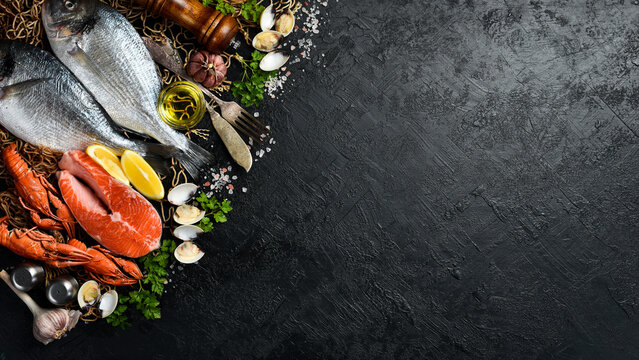 Seafood Market Banner: Fish, shellfish, crustaceans, lobster and octopus on slate black table. Free space for text or design.