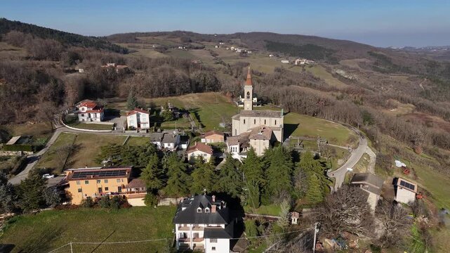 Chiesa dei Santi Salvatore e Gallo in I Rabbini, Morfasso, Piacenza, Italy showing the stone parish church with bell tower, surrounding hamlet houses, trees, and Pre and Apennine hills,Val Tolla