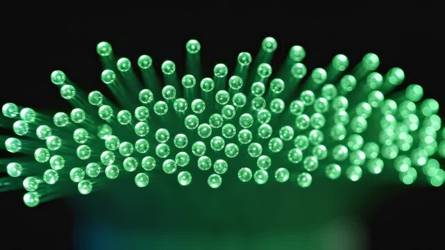 Glowing green fiber optic cables with illuminated tips on a dark background, close-up shot with bokeh effect