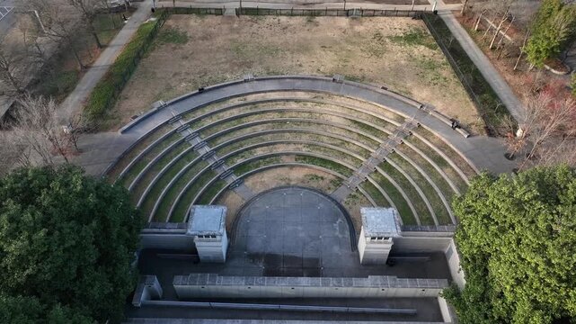 Aerial overhead view of outdoor amphitheater in Nashville, showing curved seating rows, central stage, surrounding parkland and geometric design in quiet daytime urban setting. Top down.