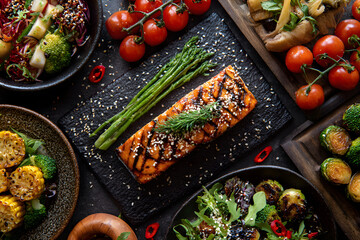 Seared salmon with asparagus, vegetables, and salad served on a table at a dining setting for a meal