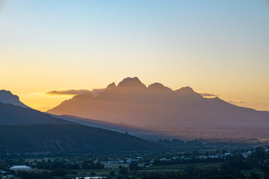 Simonsberg mountain silhouette against a golden sunset sky view from afar. Nature landscape in Stellenbosch for travel brochure.