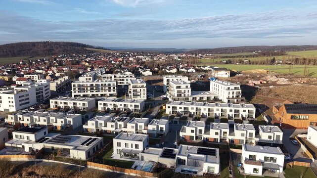 Aerial view of modern housing development. Suburban area with new construction. Sunny day with scattered clouds. Focus on architectural design. Potential for real estate or urban planning visuals