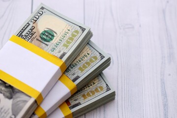 Three packs of ten thousand US dollar bills on wooden background. Packs of hundred dollar bills in stack on white wood planks close up © mehaniq41